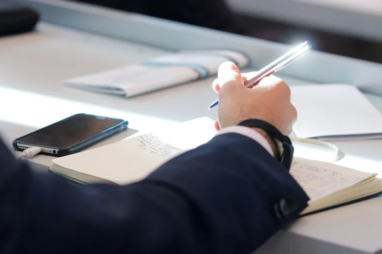 Sprachmemo in Text umwandeln: Smartphone neben handschriftlichen Notizen nach einem Termin
